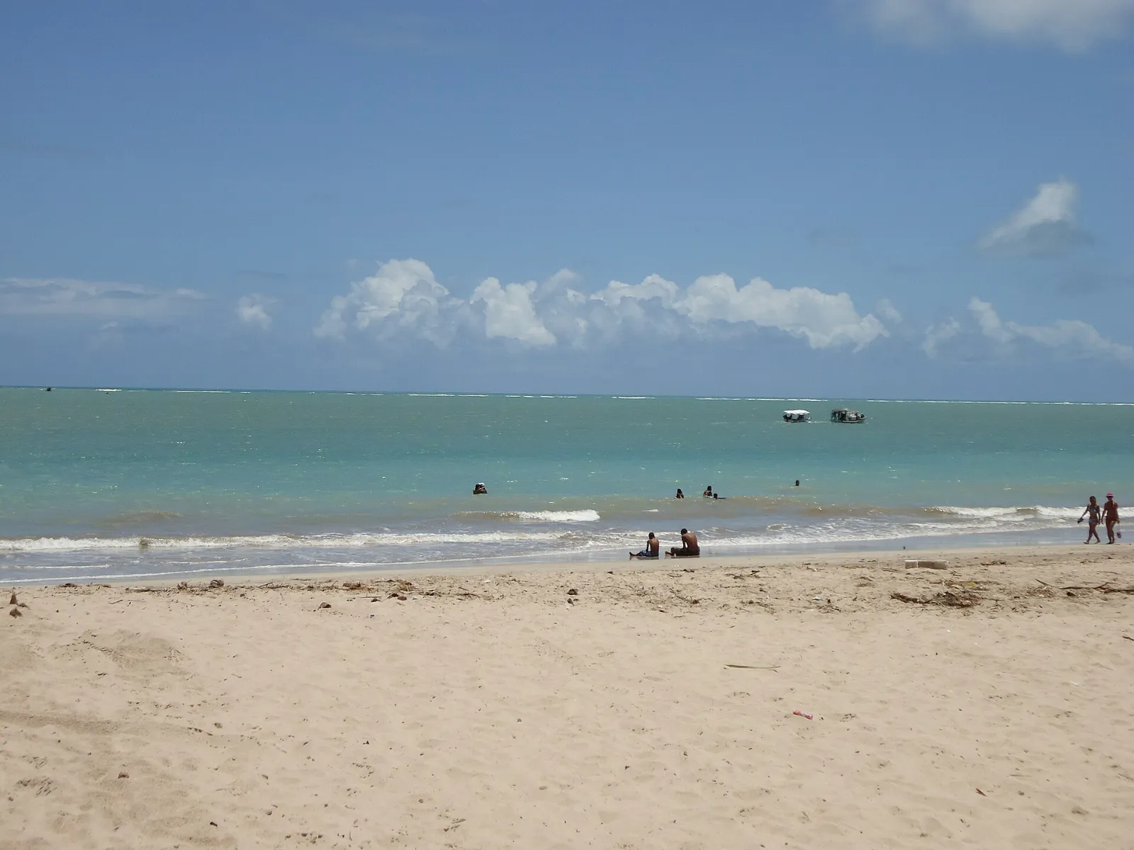 Praia de Tambaú com areia clara, mar calmo esverdeado e céu azul, em João Pessoa